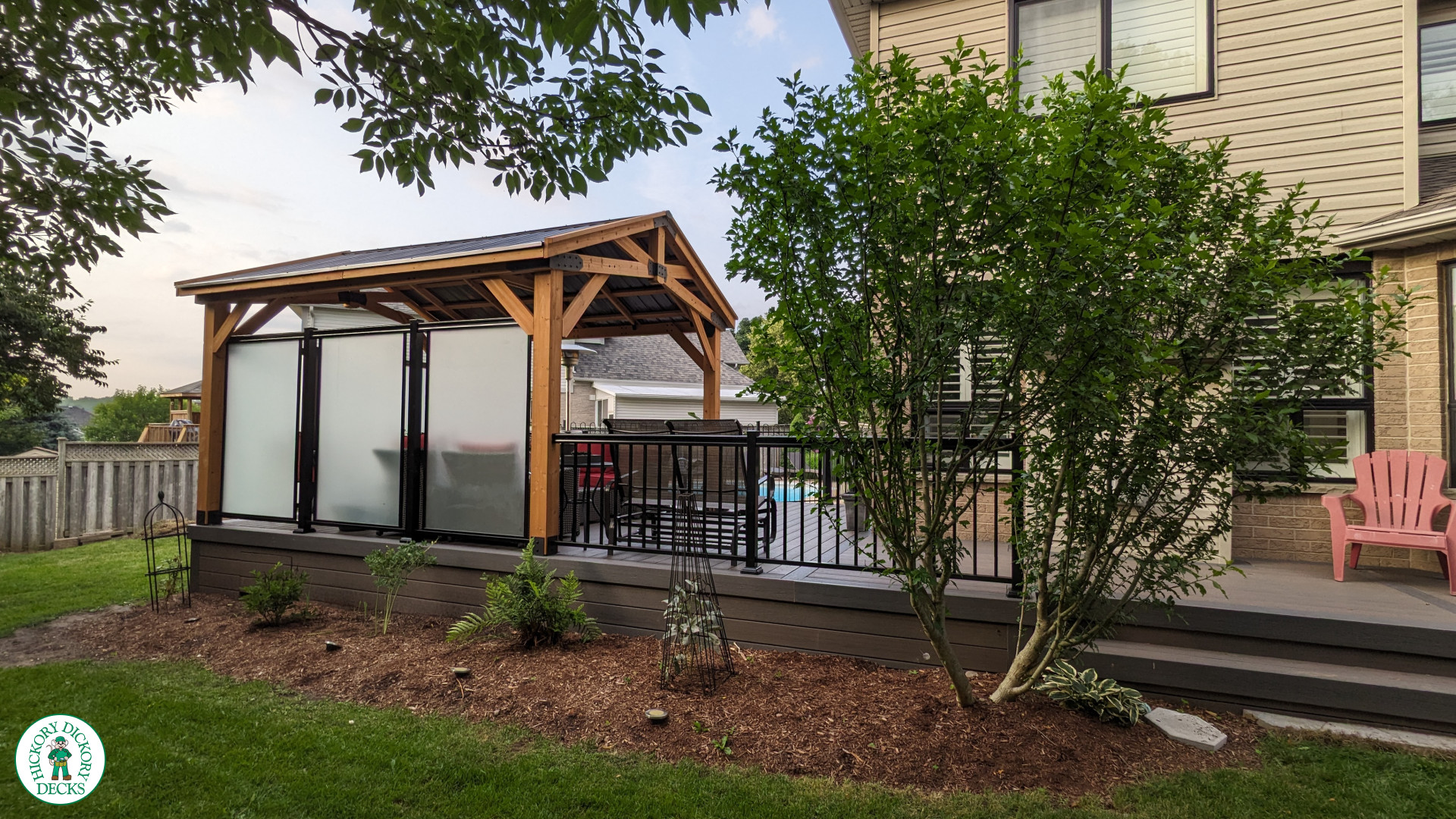 Mid size dark brown deck with dark grey border, a custom roof structure, and frosted glass privacy screens.