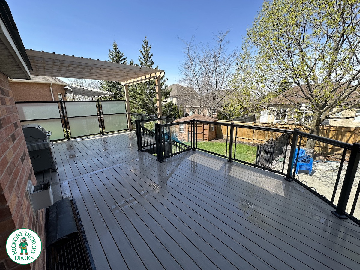 Large high deck with pergola, glass railing and frosted glass privacy screen.