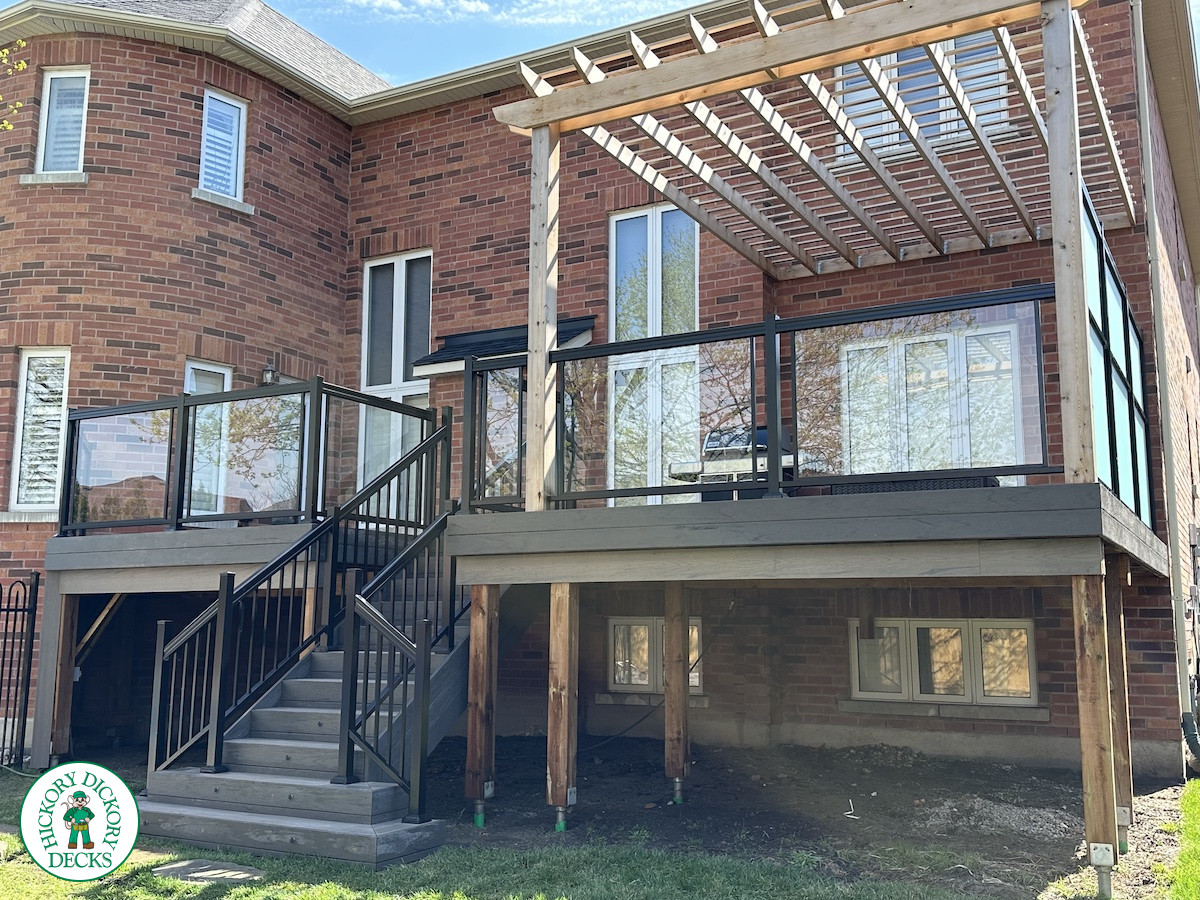 Large high deck with pergola, glass railing and frosted glass privacy screen.