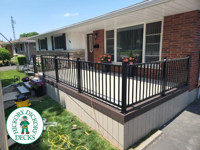 Large front porch in clay with a dark brown border and aluminum railings.