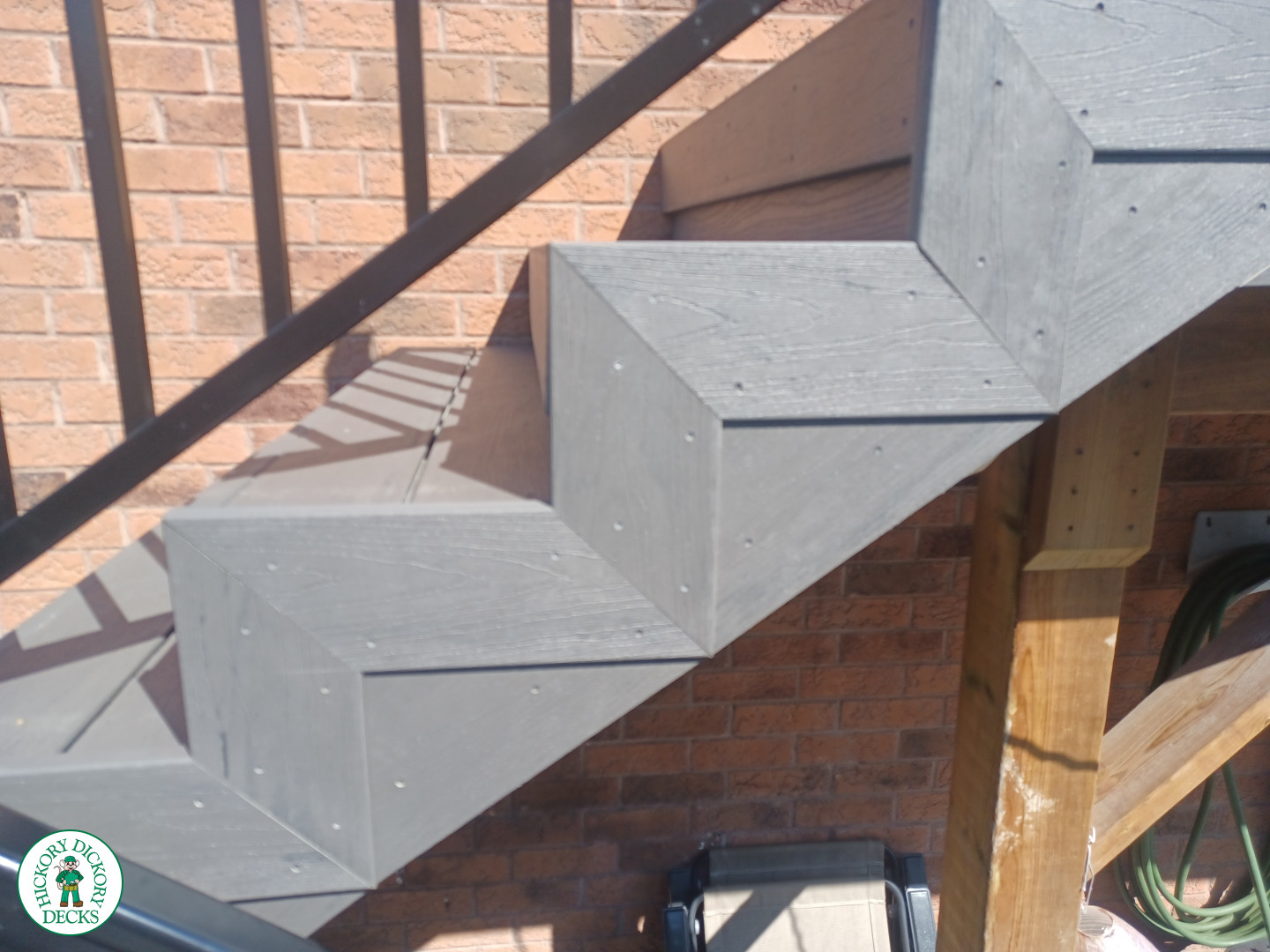Large multi level grey composite deck with cedar skirt and black aluminum railing.