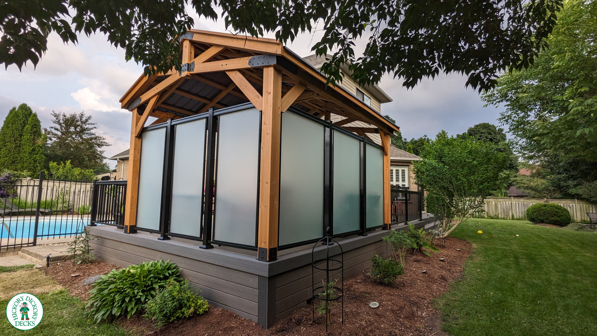 Mid size dark brown deck with dark grey border, a custom roof structure, and frosted glass privacy screens.