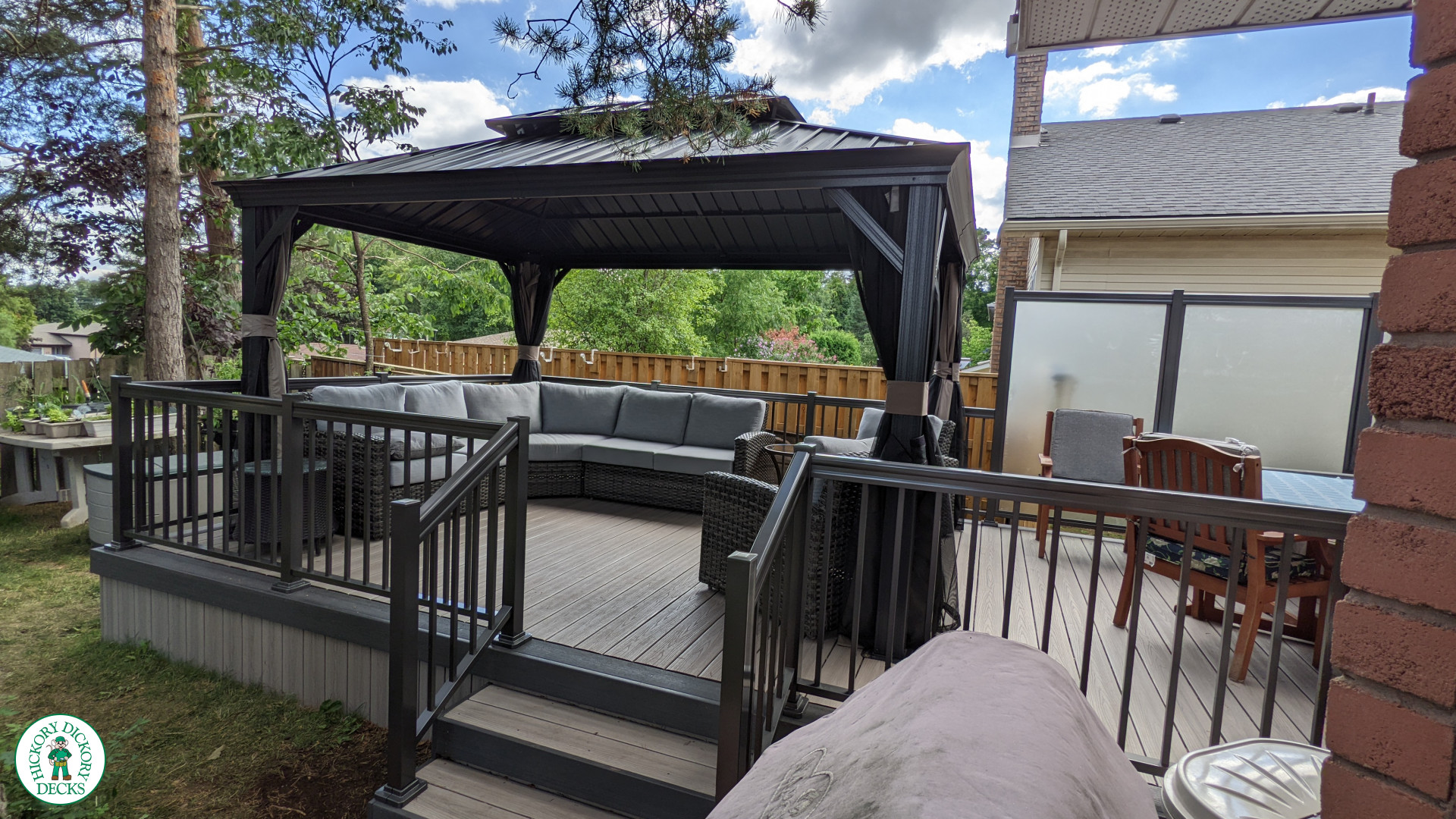 Grey composite walk out deck with dark grey borders, stained glass privacy screens, and aluminum style railing.