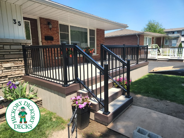 Large front porch in clay with a dark brown border and aluminum railings.