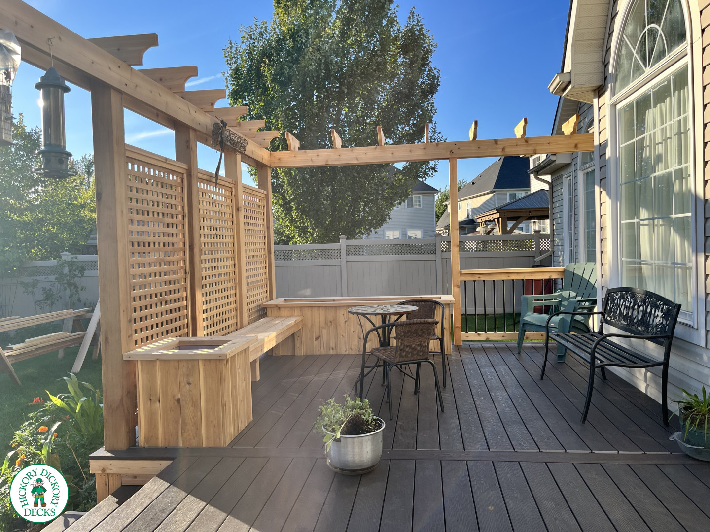 Mid size clubhouse deck in brown with cedar skirt, benches, planters, and a pergola.