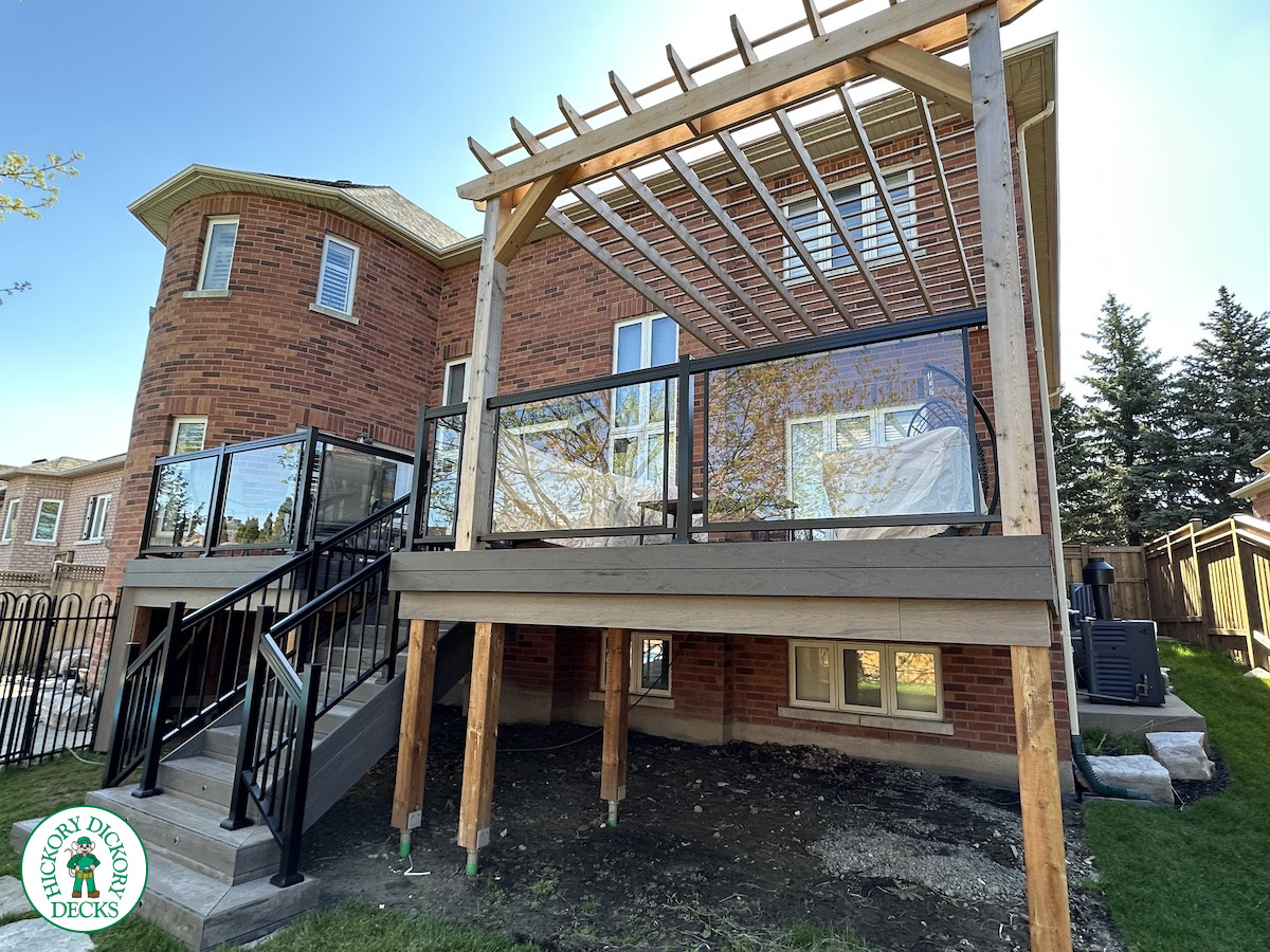 Large high deck with pergola, glass railing and frosted glass privacy screen.