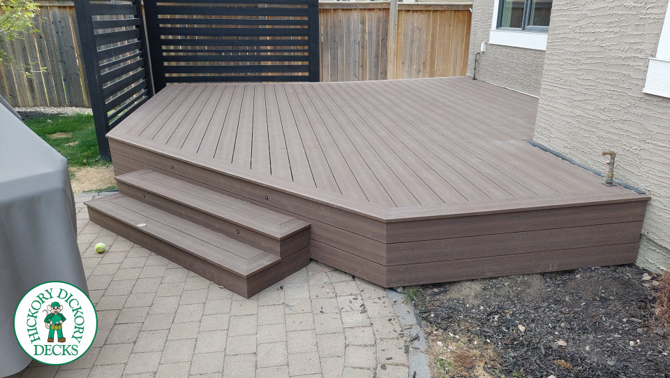 Small brown composite deck with steps and a privacy screen