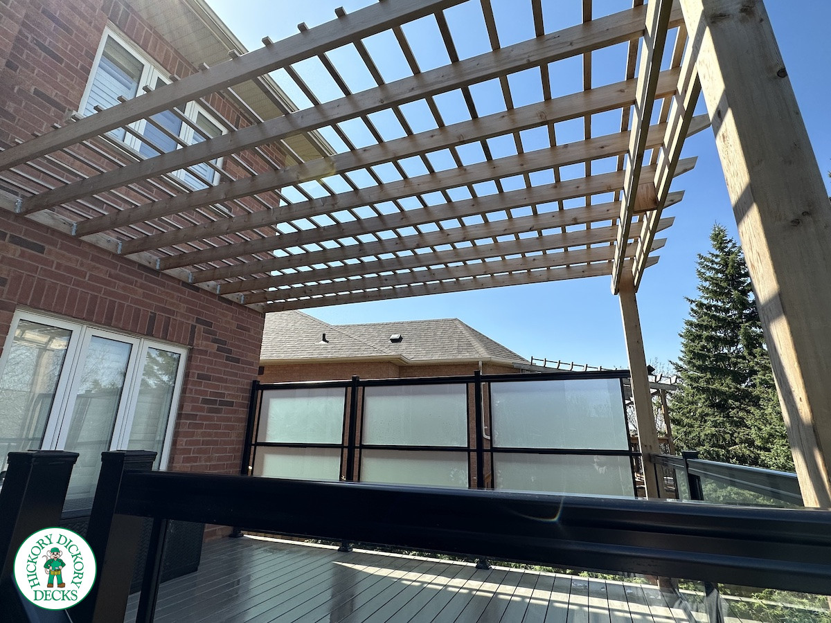 Large high deck with pergola, glass railing and frosted glass privacy screen.