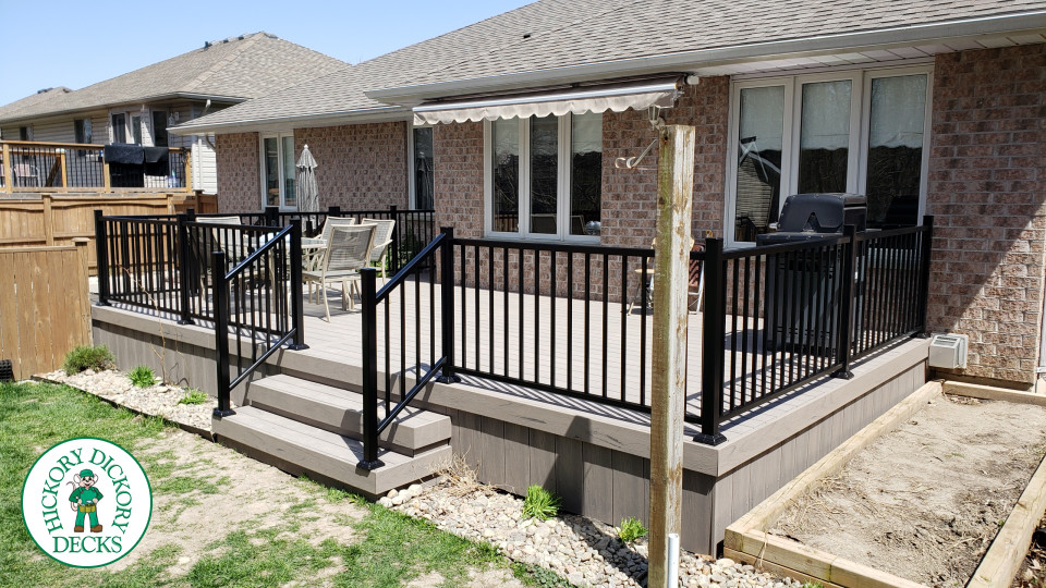 TruNorth composite deck in light grey color with three steps and black aluminum railing.