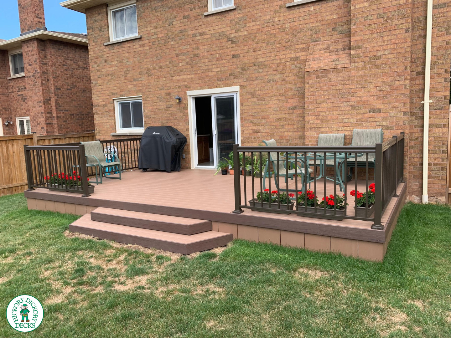 Small brown veka deck with two steps and aluminum railing.