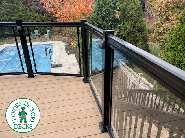 High composite deck with stairs that lead to pool and glass style railings.