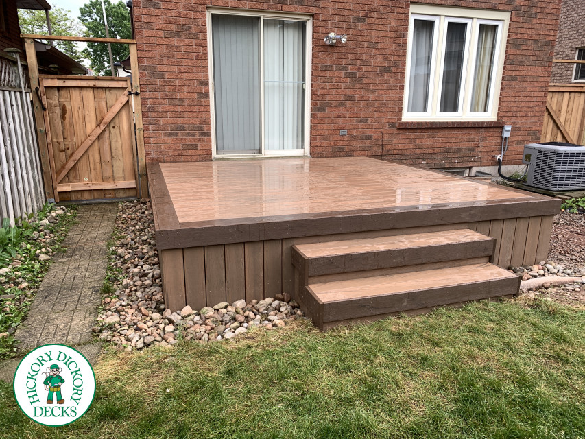 Small brown composite deck with three steps leading to yard.
