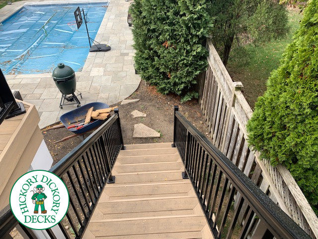 High composite deck with stairs that lead to pool and glass style railings.