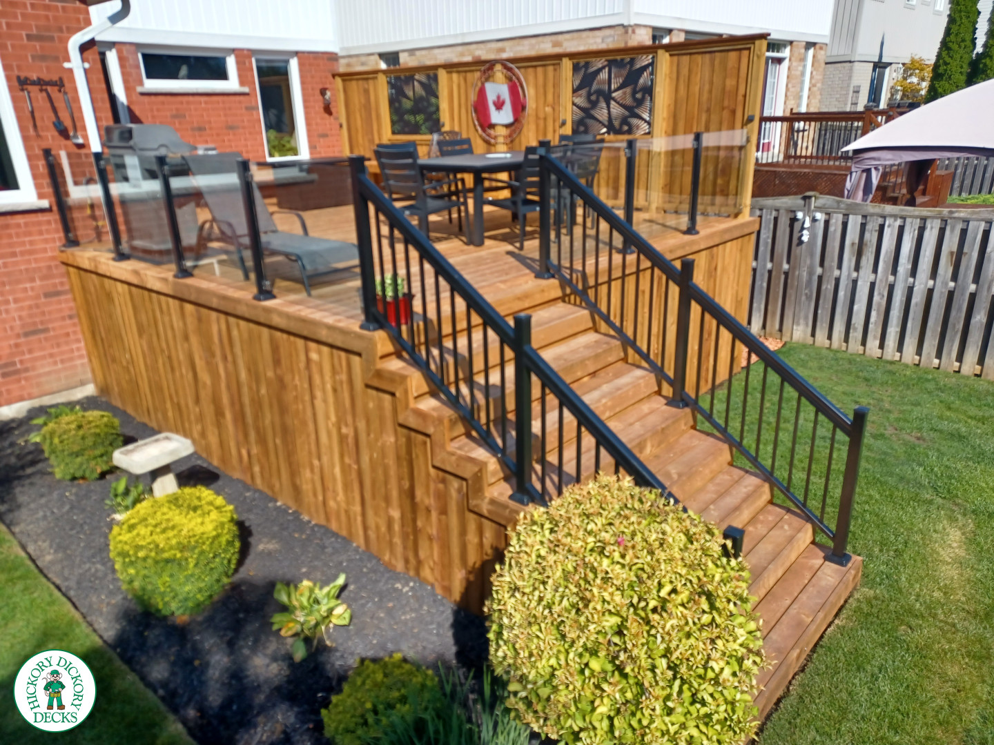 Mid rise pressure treated deck with glass railings, steps, and a custom cedar privacy screen