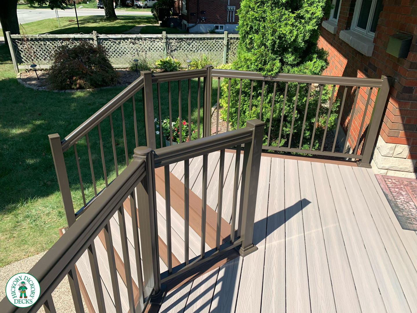 Grey front porch with brown trim and brown aluminum railing.