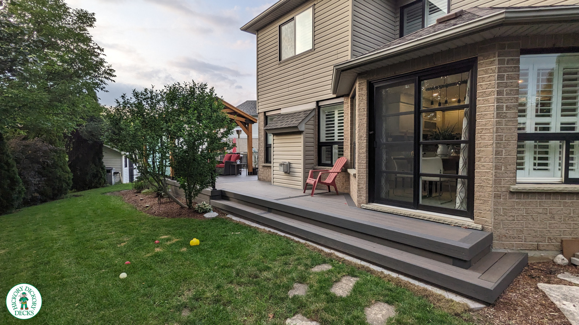 Mid size dark brown deck with dark grey border, a custom roof structure, and frosted glass privacy screens.