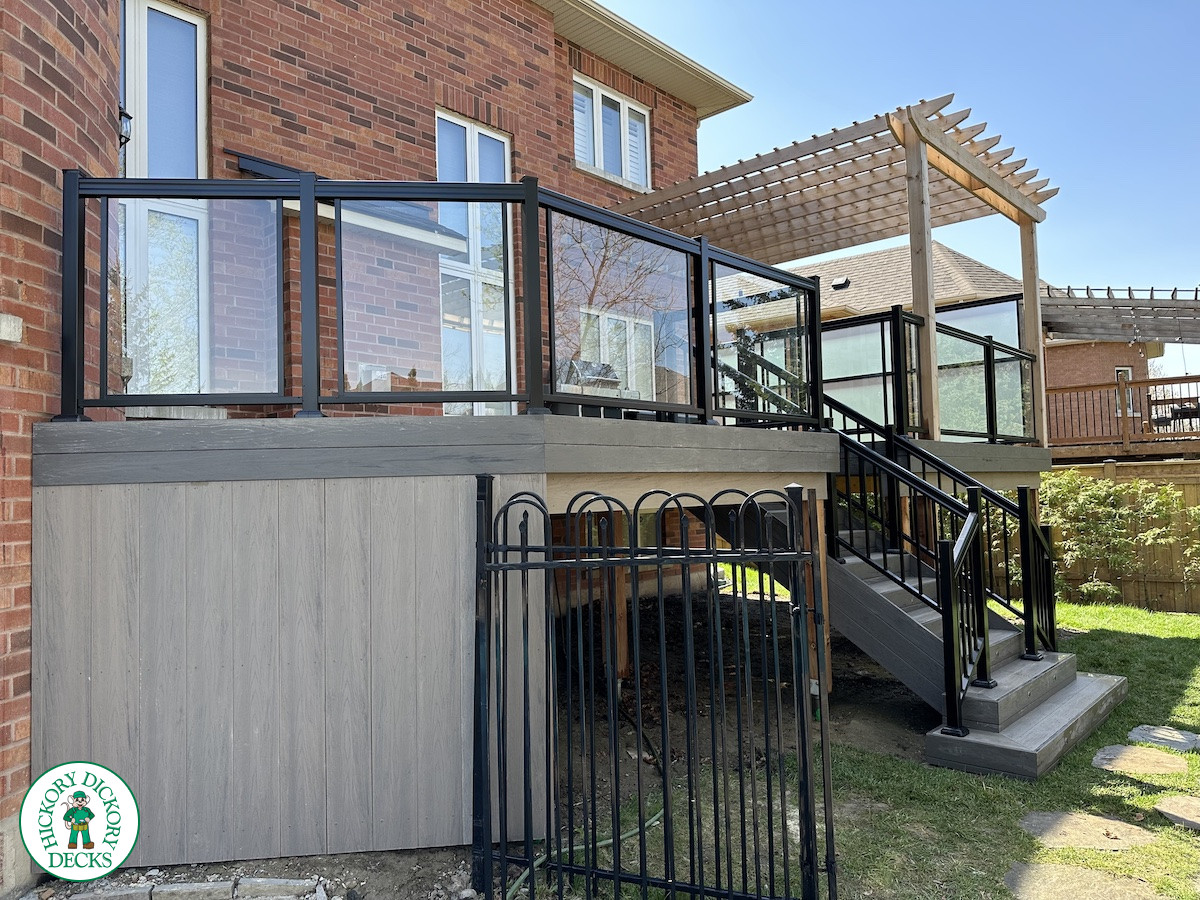 Large high deck with pergola, glass railing and frosted glass privacy screen.